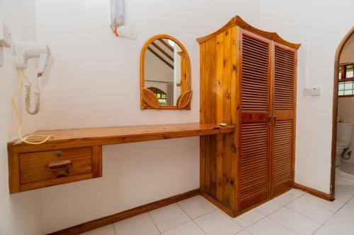 a bathroom with a wooden vanity and a mirror at Romance Bungalows in Beau Vallon