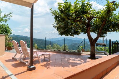eine Terrasse mit 2 Stühlen, einem Tisch und einem Baum in der Unterkunft CASA TERESA in Loppeglia