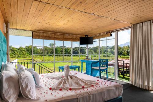 a bedroom with a bed and a balcony with windows at Elephyard Retreat in Mahiyangana