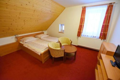 a bedroom with a bed and a table and a window at Chata Zahálka Ramzová in Ostružná