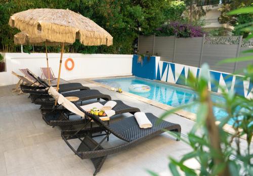 een groep stoelen en een parasol naast een zwembad bij Juliana Hotel Cannes in Cannes