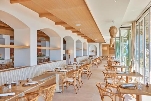 uma fila de mesas e cadeiras num restaurante em Universal Hotel Aquamarin em Sant Elm
