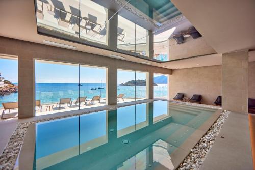 an indoor swimming pool with a view of the ocean at Universal Hotel Aquamarin in Sant Elm