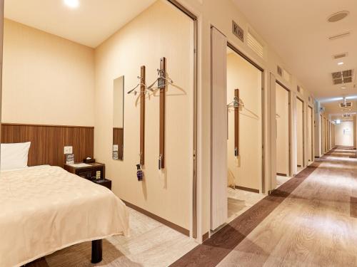 a bedroom with a bed and a row of doors at Grand Cabin Hotel Naha Oroku in Naha