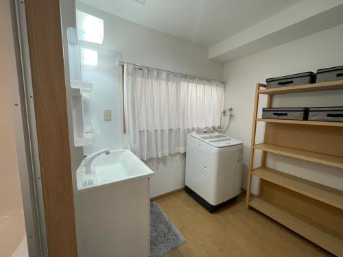 een kleine badkamer met een wastafel en een koelkast bij 青梅森の宿 in Ome