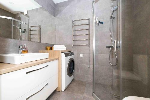 y baño con ducha y lavadora. en Mind Retreat Apartment, By Cohost en Palanga