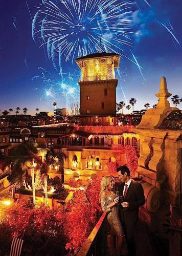 a man and a woman standing on a ledge with fireworks at The Mission Inn Hotel and Spa in Riverside