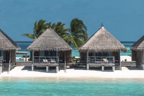 a group of huts on a beach with the ocean at Constance Moofushi Maldives - All Inclusive in Himandhoo 