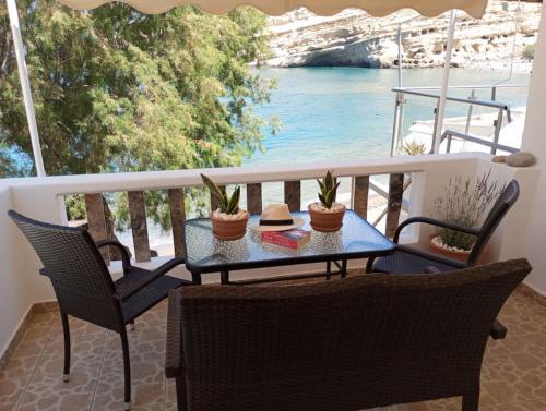 a table and chairs on a balcony with a view of the water at Seaside Nicola's Studio in Matala