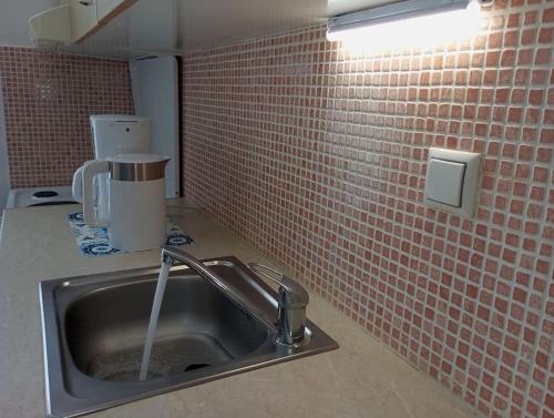 a kitchen with a sink and a red brick wall at Seaside Nicola's Studio in Matala