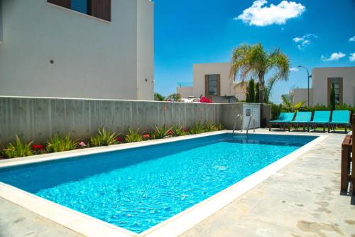 a swimming pool in front of a house at By the Beach Villa Natalya in Protaras