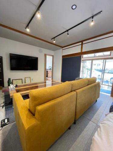 uma sala de estar com um sofá amarelo e uma mesa em Boss'sHouse犬ok天然温泉あり em Kirishima