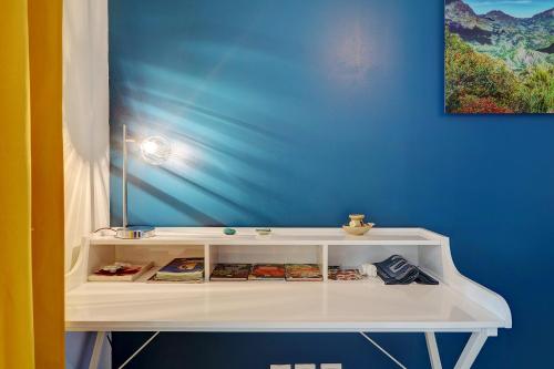 a white shelf in a room with a blue wall at T3 Le Frangipanier - Terrasse Jardin & Jacuzzi in Saint-Denis