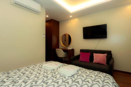 a bedroom with a bed and a chair and a television at Gloria Tree Mayon and Park View Residences in Legazpi