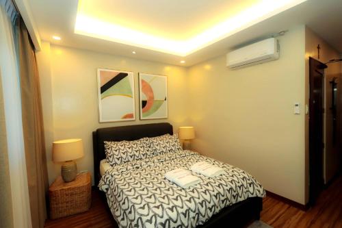 a bedroom with a bed and two pictures on the wall at Gloria Tree Mayon and Park View Residences in Legazpi