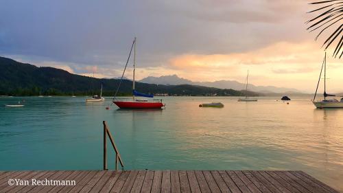 a group of boats on a lake with mountains at Villa Auguste in Pörtschach am Wörthersee