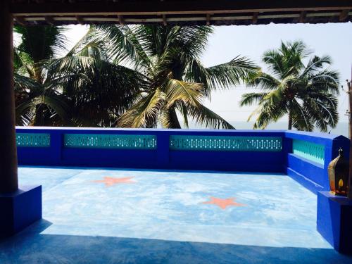 a swimming pool with palm trees in the background at Majo House in Cherai Beach