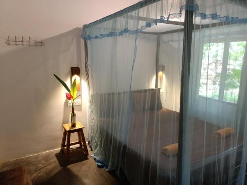 1 dormitorio con ventana y un jarrón con una flor en una mesa en Ocean Bliss, en Pottuvil