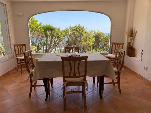 ein Esszimmer mit Tisch und Stühlen und einem großen Fenster in der Unterkunft Villa Belinda in Santa Margherita di Pula