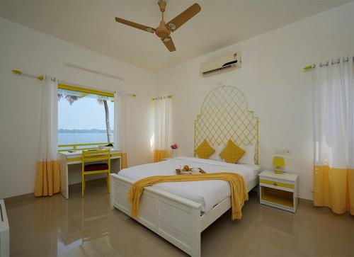 - une chambre avec un grand lit blanc et une fenêtre dans l'établissement Seclude by the Lake, Alleppey, à Alappuzha
