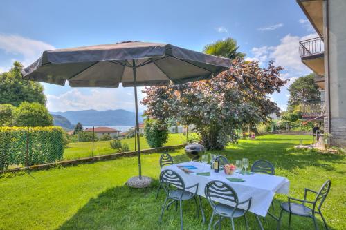 einen Tisch und Stühle unter einem Regenschirm im Gras in der Unterkunft Residenza Il Parco Family Retreat in Ispra
