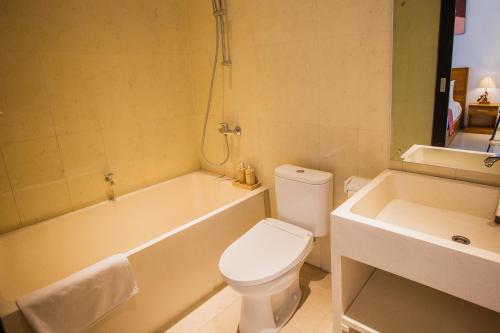 a bathroom with a toilet and a tub and a sink at Penida Paradiso in Klungkung