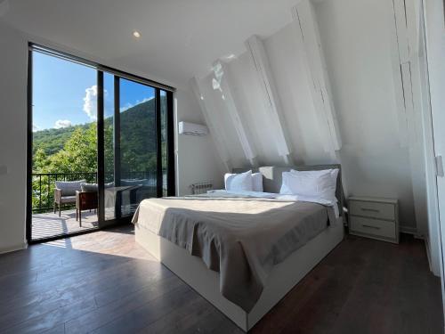 a bedroom with a large bed and a large window at Qafqaz Falcon Chalet in Gabala