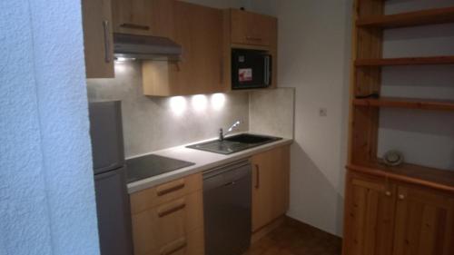 une petite cuisine avec un évier et un réfrigérateur dans l'établissement Deux pièces Monêtier-les-Bains (Serre-Chevalier), au Monêtier-les-Bains