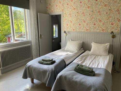 Dos camas en una habitación con toallas. en Pensionat Grisslehamn, en Grisslehamn