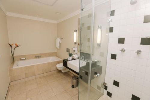 a bathroom with a tub and a toilet and a shower at Mandela Rhodes Place in Cape Town