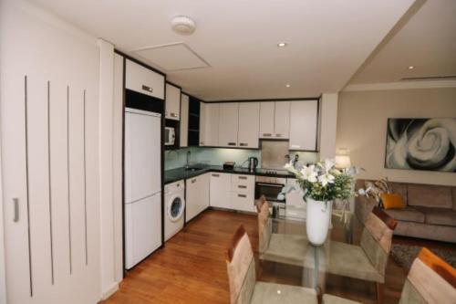 a kitchen with white cabinets and a vase of flowers at Mandela Rhodes Place in Cape Town