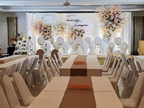 a long table and chairs in a room with flowers at แกรนด์ ฟอเรสท์ Grand Forest in Chanthaburi