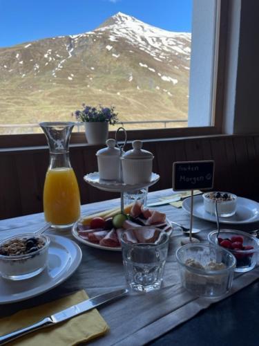 a table with breakfast food and a window with a mountain at Hotel Bergalga in Am Bach