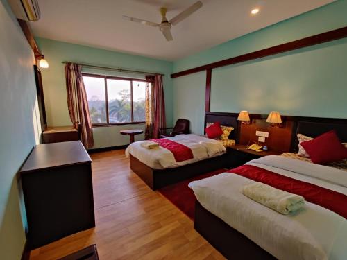 a hotel room with two beds and a window at Hotel Ananda Inn in Lumbini