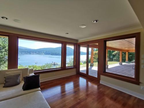 a living room with a couch and large windows at Deep Cove Stunning Waterfront Whole House in North Vancouver