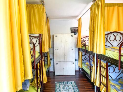 a room with four beds and yellow curtains at Hi Skopje Hostel in Skopje