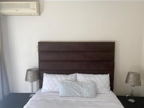a bedroom with a bed with a brown headboard and two lamps at Safari Apartments -Beautiful 3 bedrooms, 10-seater dining , TV room, Garden & Pool in Johannesburg