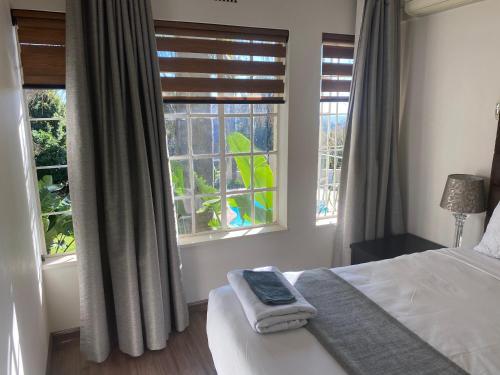 a bedroom with a bed and two windows at Safari Apartments -Beautiful 3 bedrooms, 10-seater dining , TV room, Garden & Pool in Johannesburg