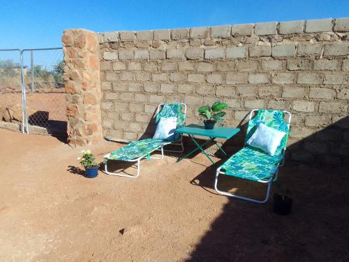 twee stoelen en een tafel voor een stenen muur bij KGOLA SAFARIS in Rosslyn