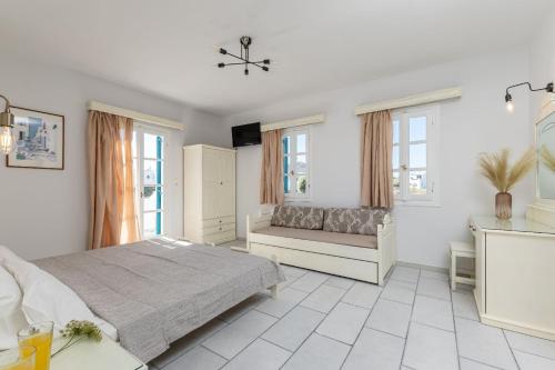 a white bedroom with a bed and a couch at Golden Silence Studios in Agios Prokopios