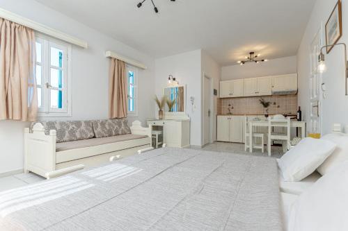 a white living room with a couch and a kitchen at Golden Silence Studios in Agios Prokopios
