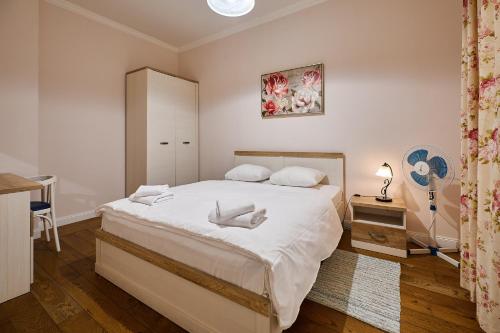 Un dormitorio con una gran cama blanca y una mesa en Stabu Sēta Apartments, en Riga