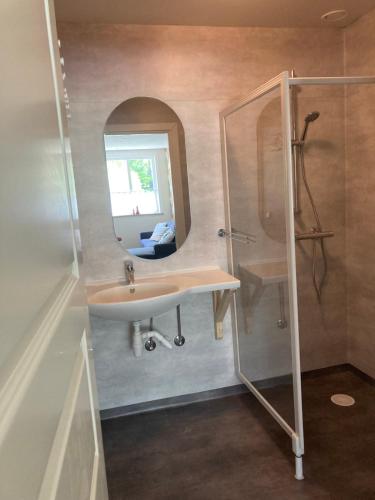a bathroom with a sink and a shower with a mirror at Härlig Heden Vakantie Appartement in Råda
