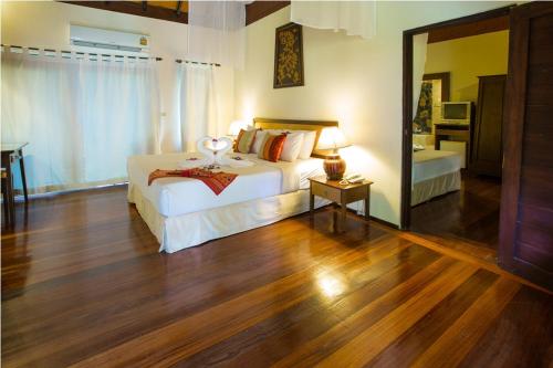 a bedroom with a white bed and a large mirror at Golden Pine Resort and Spa in Ban Du