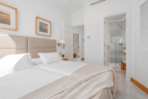 a white bedroom with a white bed and a bathroom at Parque Santiago IV Official in Playa de las Americas