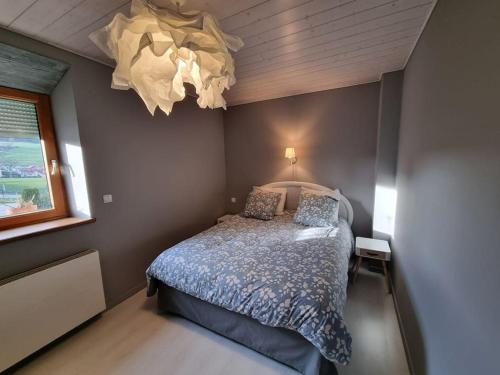 1 dormitorio con cama y lámpara de araña en Logement dans maison + extérieur, en Orchamps-Vennes