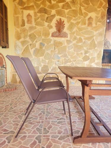 a table and chair next to a table and a stone wall at Ancient Greek Villa in Schinias