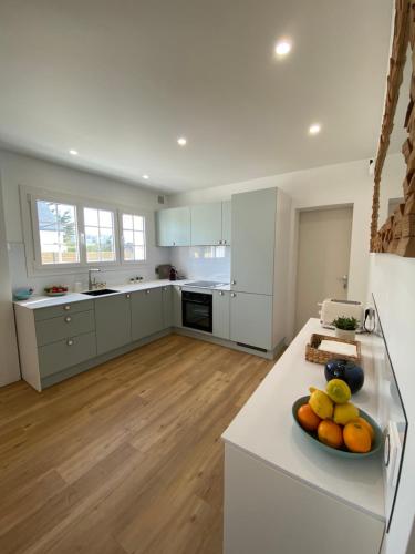 une cuisine avec des armoires blanches et un bol de fruits sur un comptoir dans l'établissement Quiberon, à Quiberon