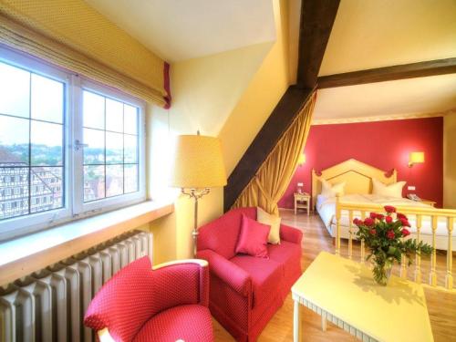 a living room with red chairs and a bed at Trip Inn Hotel Der Adelshof in Schwäbisch Hall