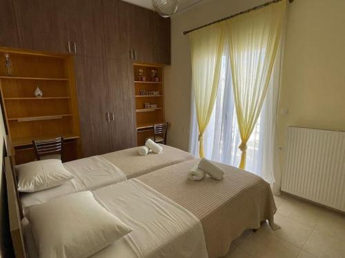 una camera con due letti con lenzuola bianche e una finestra di Rita's Apartment a Heraklion